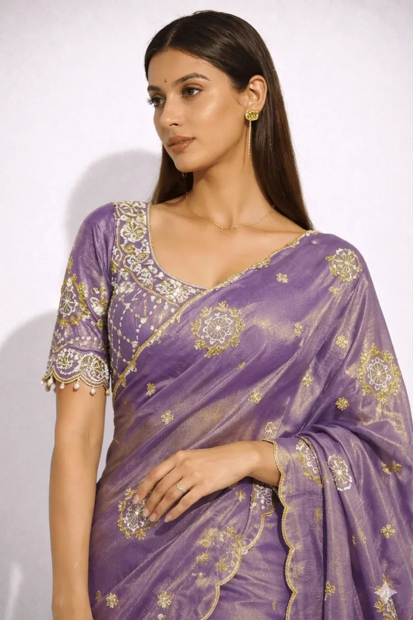 Woman wearing a purple saree with gold patterns on a white background